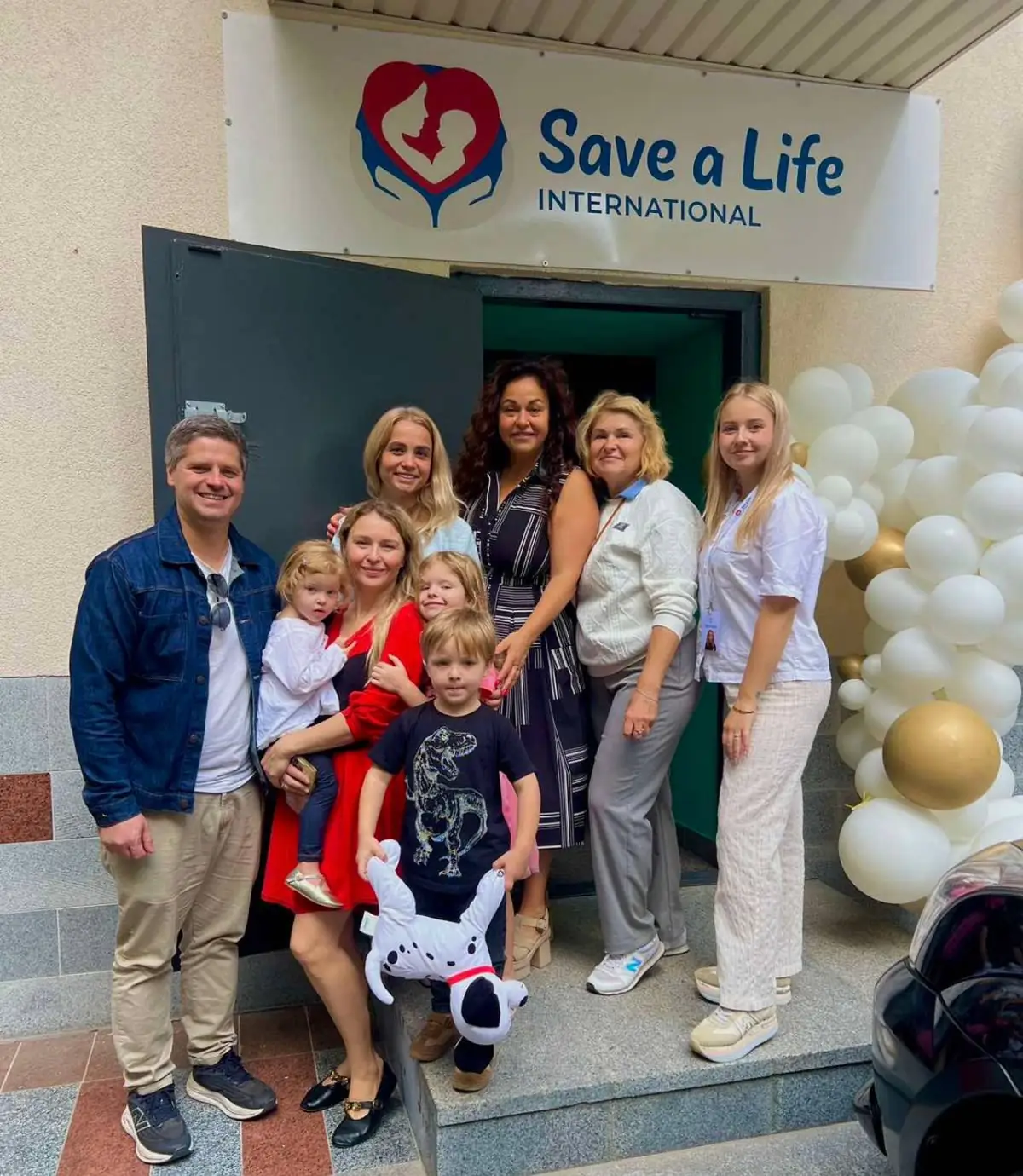 Mothers, children, and team members gather outside a Life Center in Ukraine, under the Save a Life International sign, to celebrate A Day of Hope.