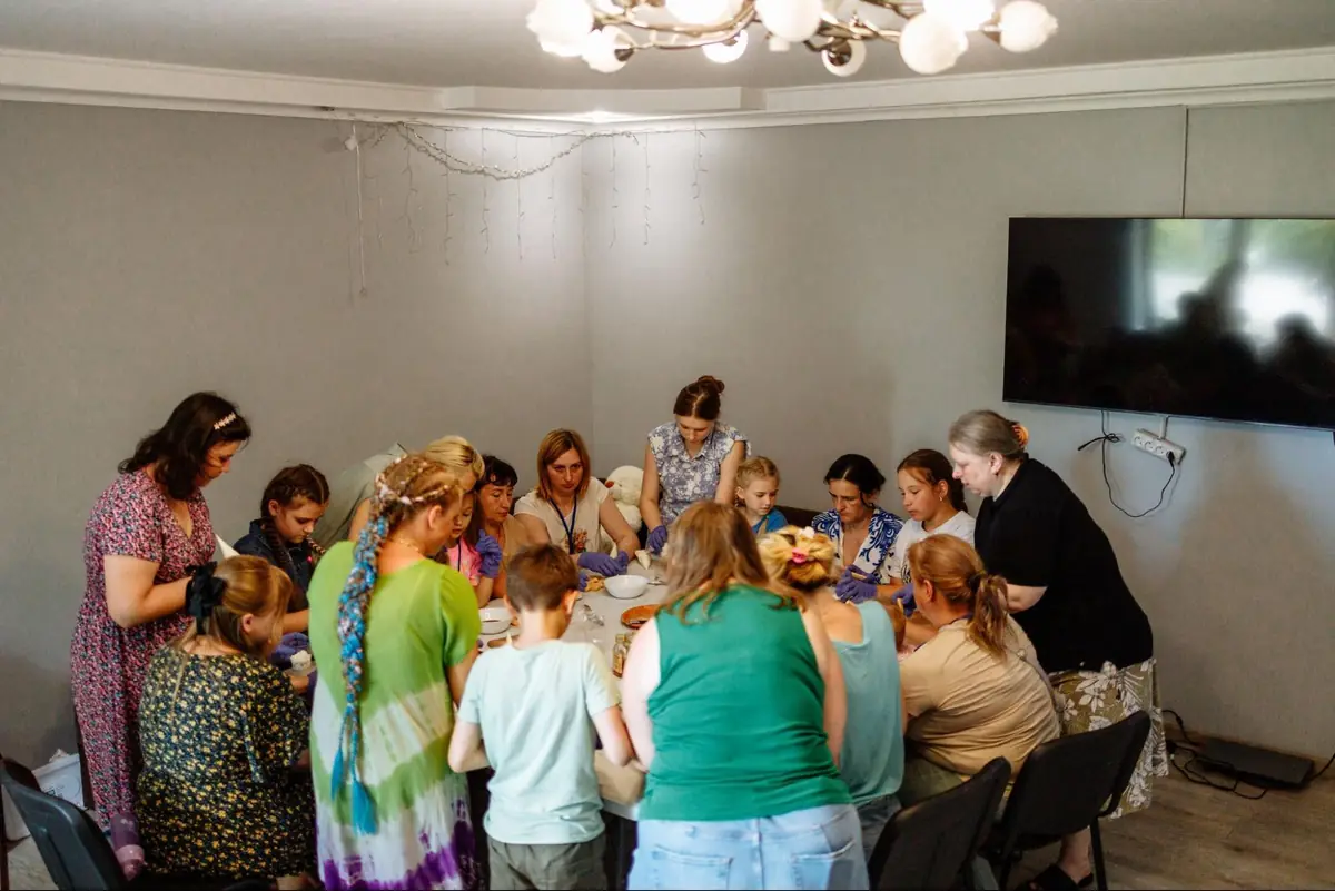 Mothers and children stand together around a table during an activity at the “More Than Words” camp.
