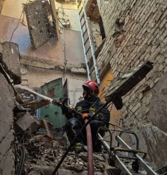 A firefighter works to extinguish the flames inside a building left in ruins after the strike.